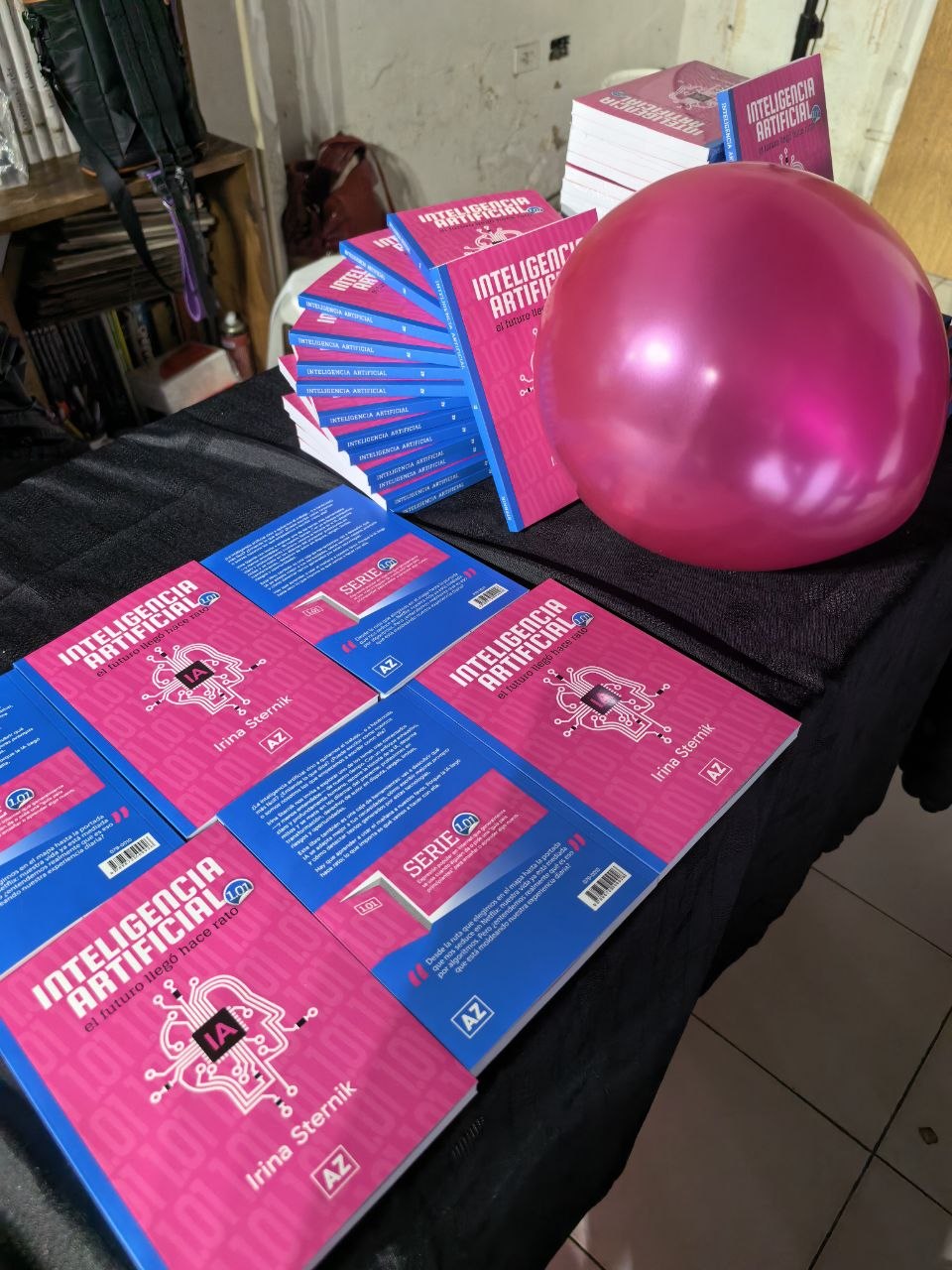 Ejemplares de Inteligencia Artificial 1.01 sobre la mesa, junto a un globo fucsia